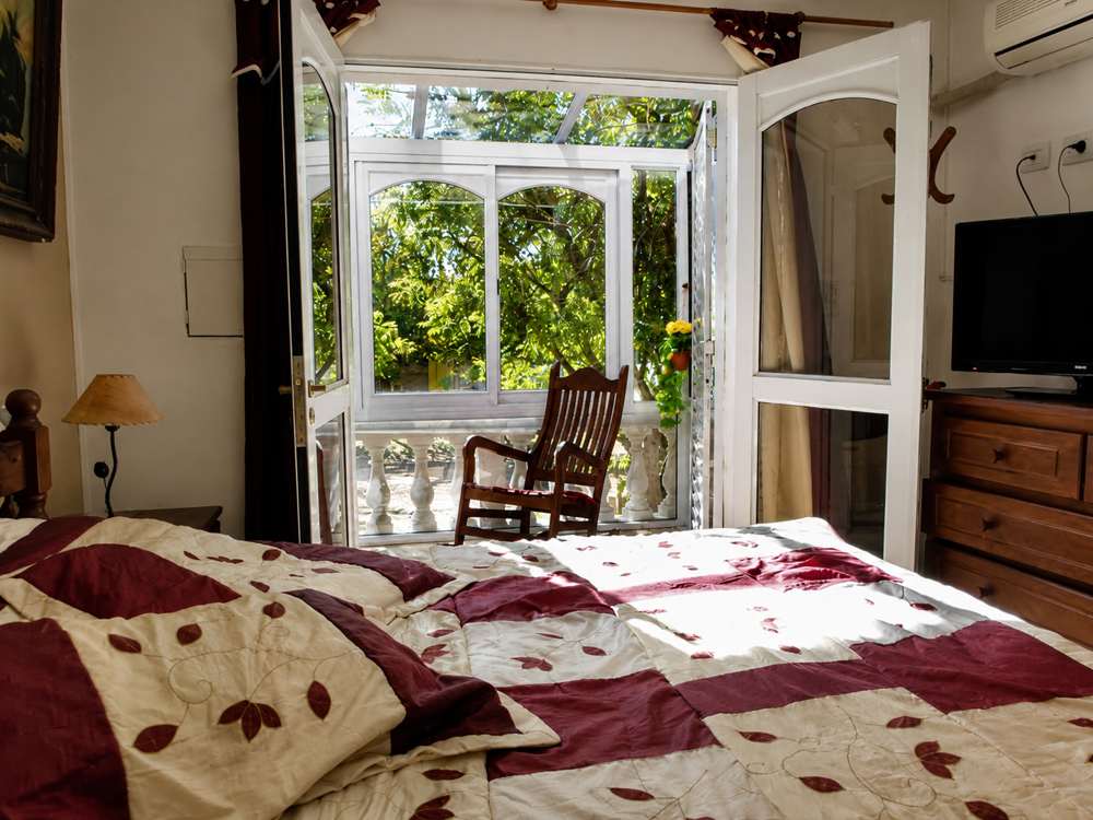 Habitación con puertas que dan a un pequeño balcón rodeado de árboles verdes