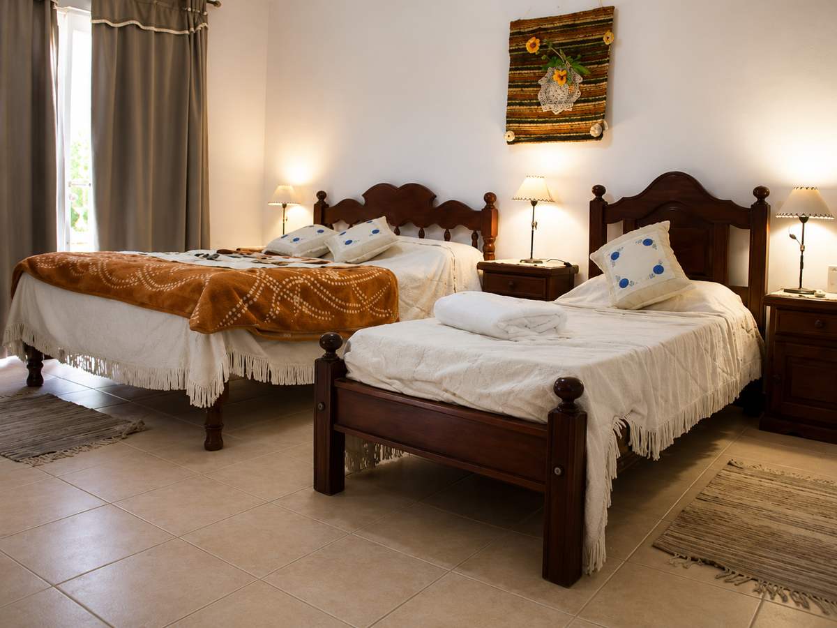 Habitación con dos camas de madera, mesa de luz y una tela decorativa en la pared